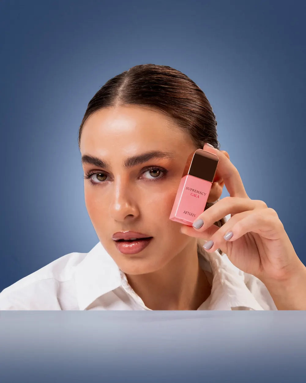 A woman holding a pink bottle against her cheek