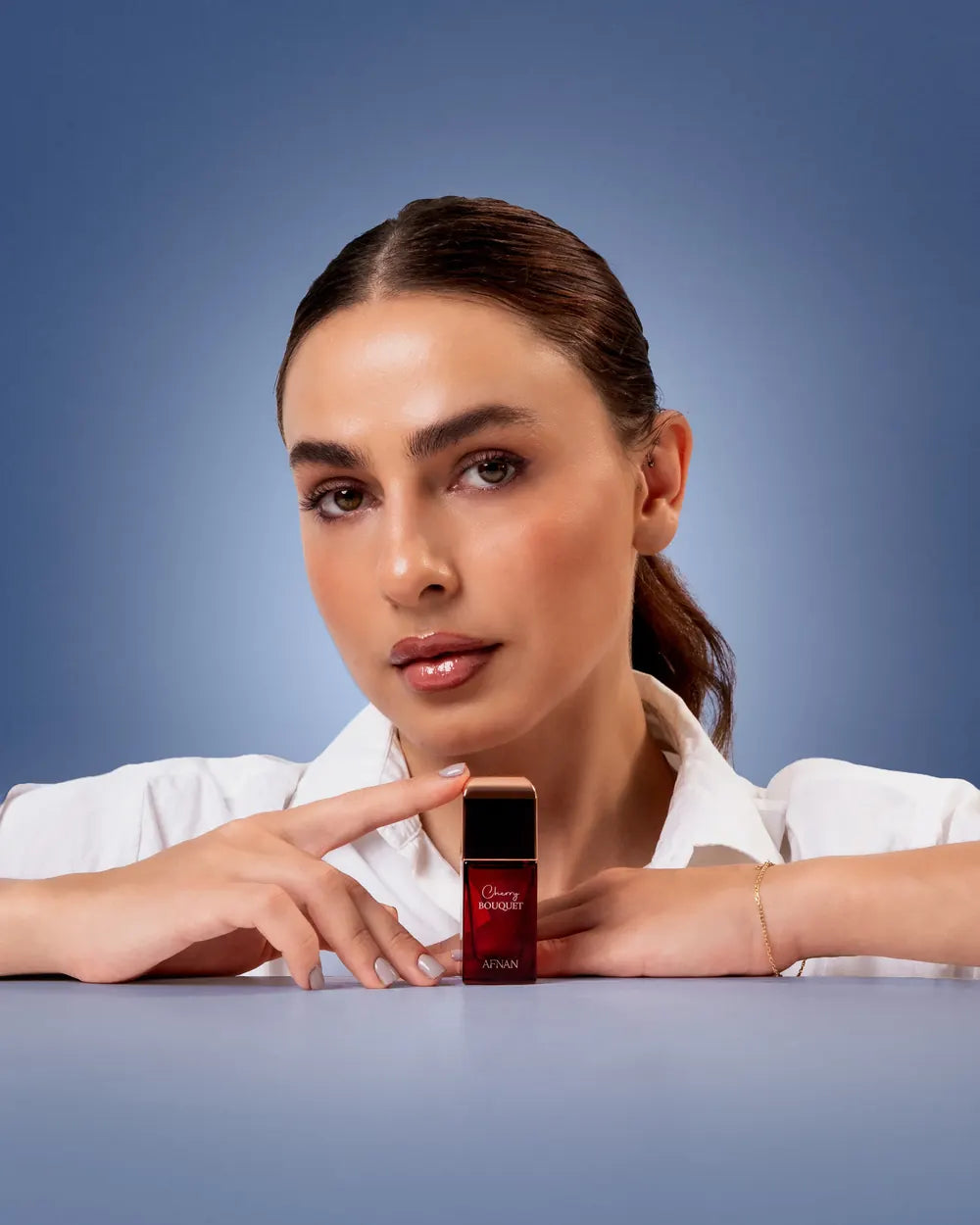 A woman resting her chin on her hands beside a single bottle